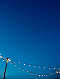 Low angle view of lights against clear blue sky