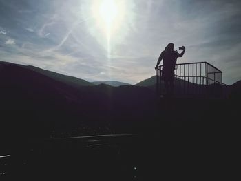 Silhouette man photographing while standing by railing against sky at montferrat