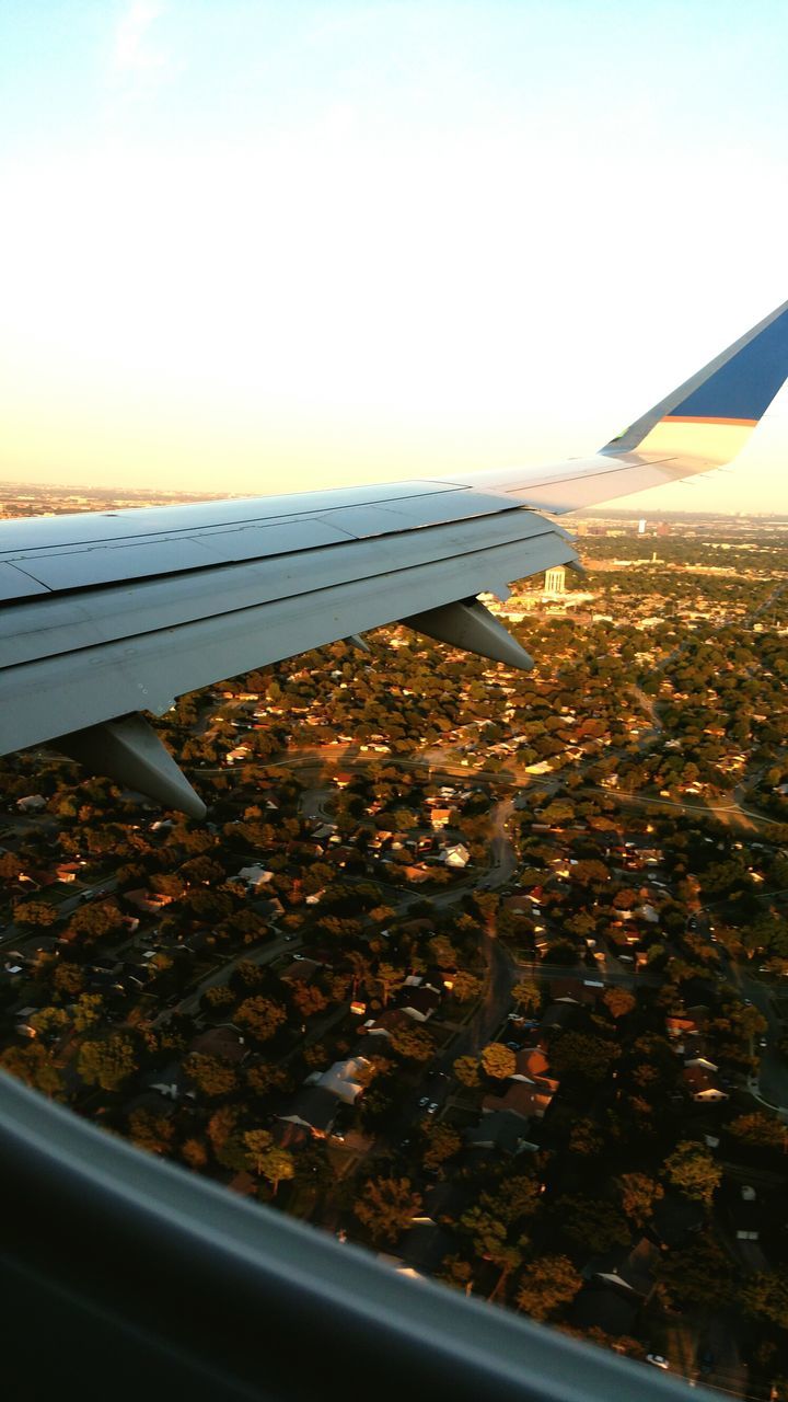 aerial view, transportation, airplane, flying, air vehicle, mode of transport, aircraft wing, sea, sky, cityscape, part of, cropped, water, travel, scenics, sunset, city, mid-air, high angle view, nature