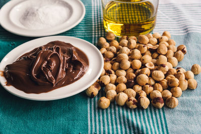 Close-up of chocolate and hazelnuts with flour by oil bottle on table