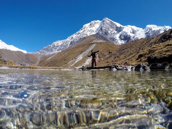 Surface level view of lake against man with snowcapped mountains in background