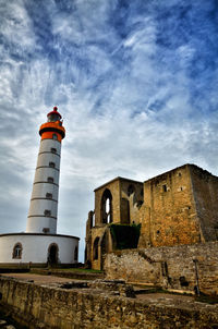 Low angle view of lighthouse by building against sky