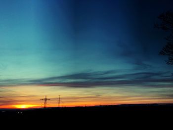 Silhouette electricity pylon against sky at sunset