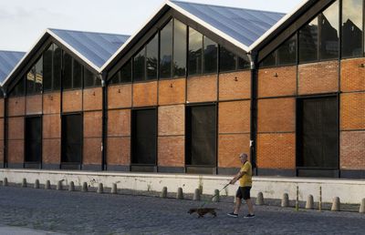 Man walking on footpath by building