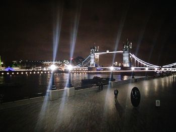 Illuminated suspension bridge against sky at night