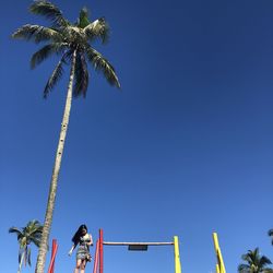 Low angle view of palm trees against clear blue sky