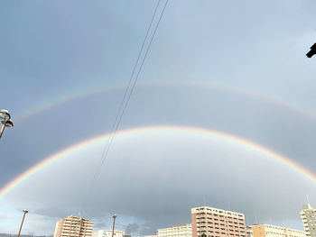 Low angle view of rainbow over buildings in city