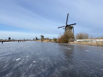 Traditional windmill on snow covered landscape against sky