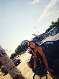 Portrait of young woman in city against sky