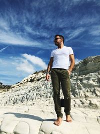 Full length of man standing on rock formation against sky