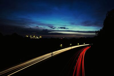 Light trails on road against sky at night