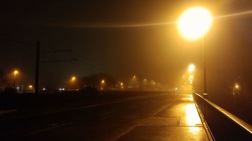 Illuminated railroad tracks against sky at night