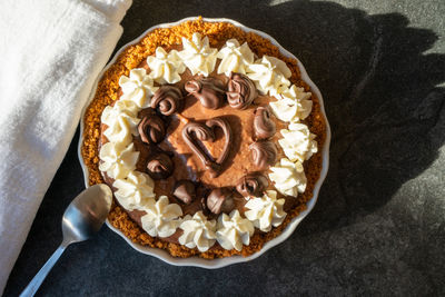 High angle view of chocolate-orange tart with cream and heart decoration