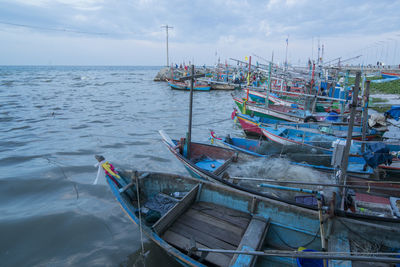 Fishing boats moored in sea against sky