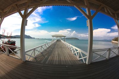 Pier on sea against cloudy sky