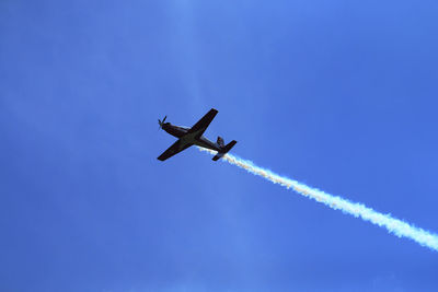 Low angle view of airplane flying against clear blue sky