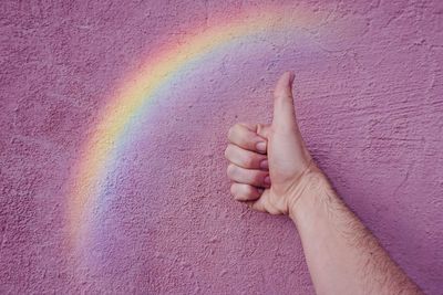 Hand with a rainbow on the pink wall. lgbt symbol