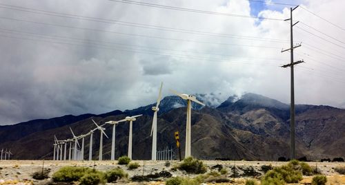 Electricity pylon by mountains against sky