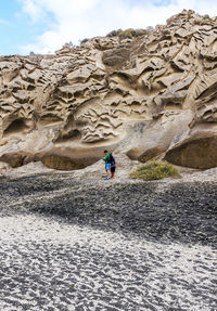 People on rock formation against sky