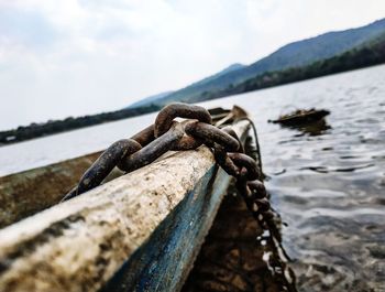 Close-up of rusty chain on boat in sea against sky