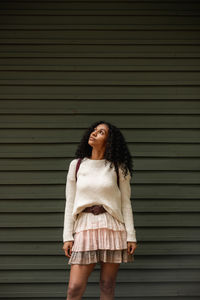 Adult african american female tourist standing on walkway with faded leaves and looking up in monte verde of costa rica