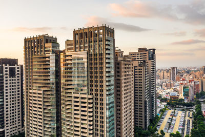 Modern buildings in city against sky during sunset