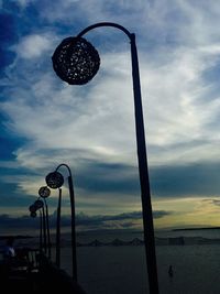 Silhouette of lamp post against cloudy sky