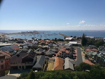 Cityscape by sea against blue sky