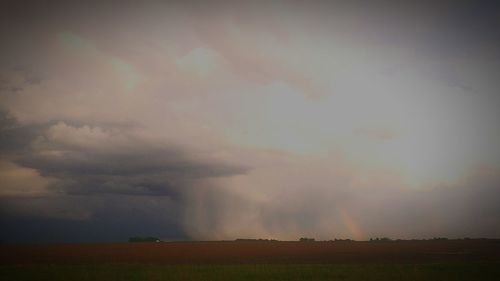 Scenic view of field against storm clouds