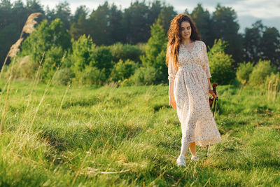 Portrait of young attractive woman standing with violin on the grassy field