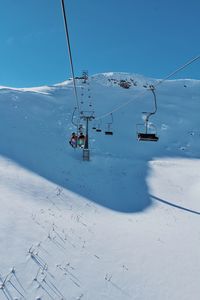 Overhead cable car on snowcapped mountains against sky