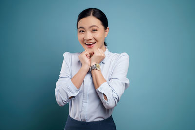 Portrait of a smiling young woman against blue background