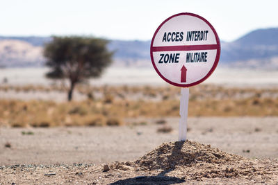 Information sign on field by road against sky