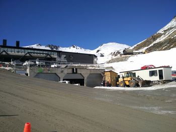 Houses against snowcapped mountains against clear blue sky