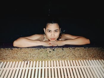 Portrait of a young woman sitting against black background