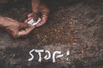 Cropped hands rolling cigarettes outdoors