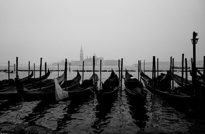 Wooden posts moored in water against clear sky