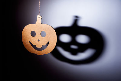 Wooden pumpkin decoration hanging against shadow on wall during halloween