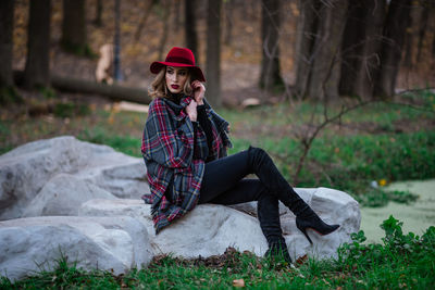 Young woman sitting on field in forest