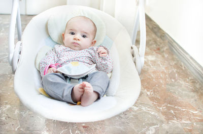 Cute baby girl sitting in bedroom