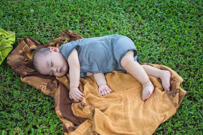High angle view of baby boy sleeping on shawl at field