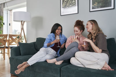 Young woman using phone while sitting on sofa at home