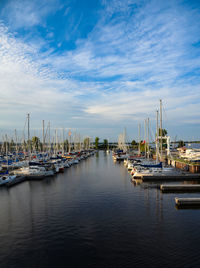 Sailboats moored at harbor against sky