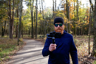 Man photographing while standing on footpath in forest