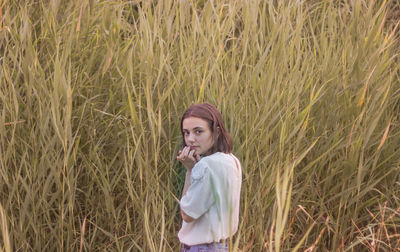 Portrait of young woman standing on field