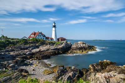 Lighthouse by sea against sky