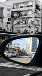 View of city street seen through side-view mirror