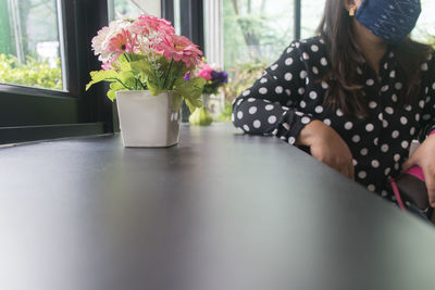 Midsection of woman sitting on table at home