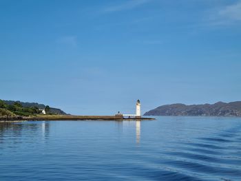 Scenic view of sea against blue sky featuring lighthouse