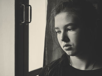 Close-up of thoughtful girl looking through window at home